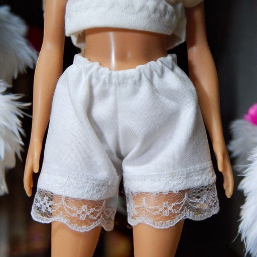 Fehér csipkés vászon rövidnadrág barbie babákhoz előlnézet, fehér háttér
