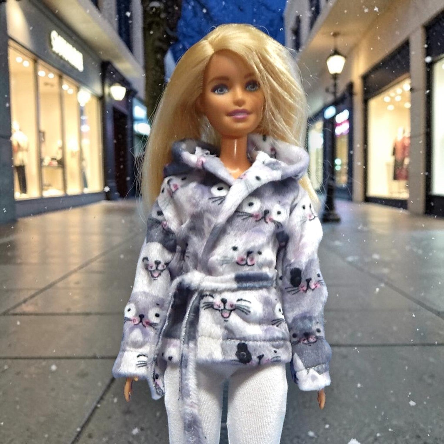 Cicamintás szürke-fehér minky kabát kézműves babaruha Barbie típusú divatbabákhoz – sálgalléros, átlapolódó fazon rögzített övvel, havas bevásárlóutca előtt, Barbie ruha, divatbaba ruha, kézműves babaruha, Nikols Design.

